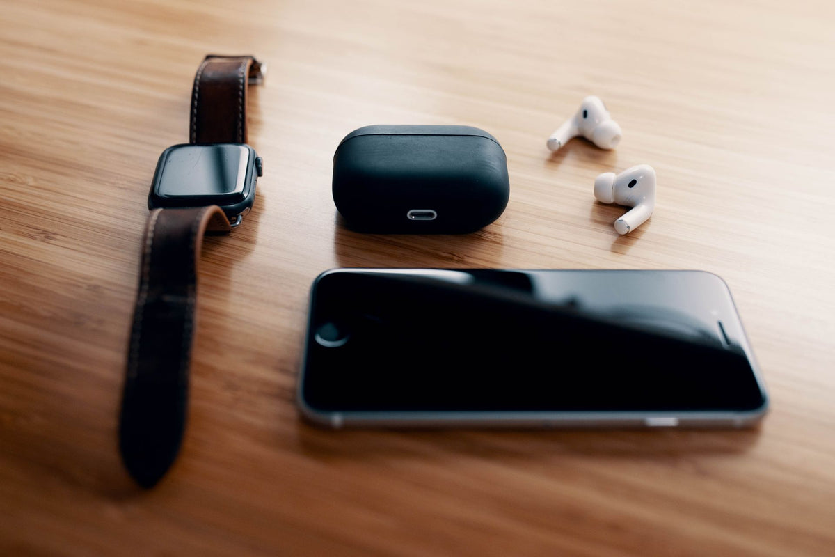 Smartwatch, wireless earbuds and phone on a wooden desk